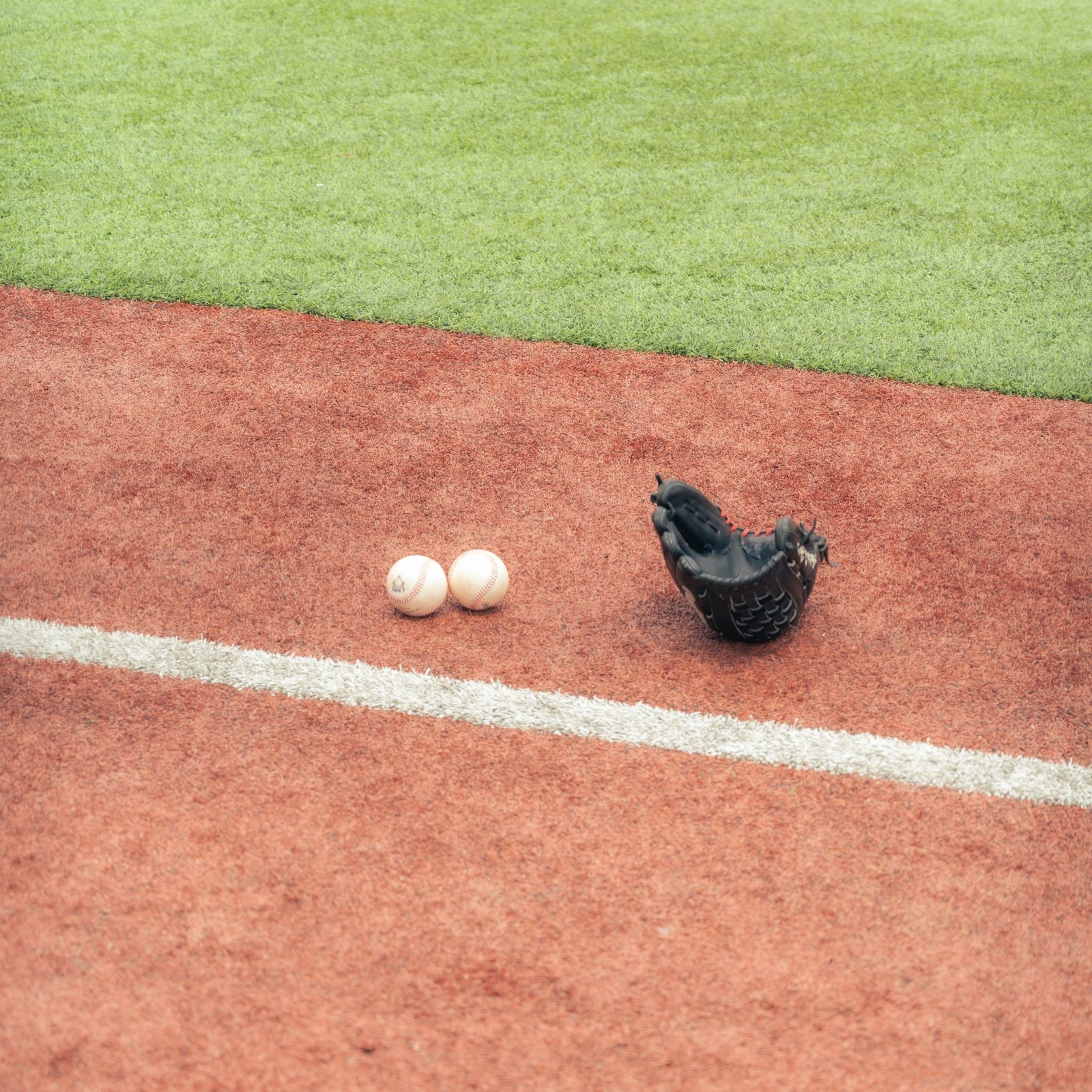 Baseball glove and balls on turf field