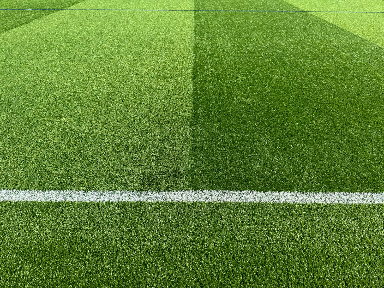 Close-up of vibrant green football field turf with white line marking